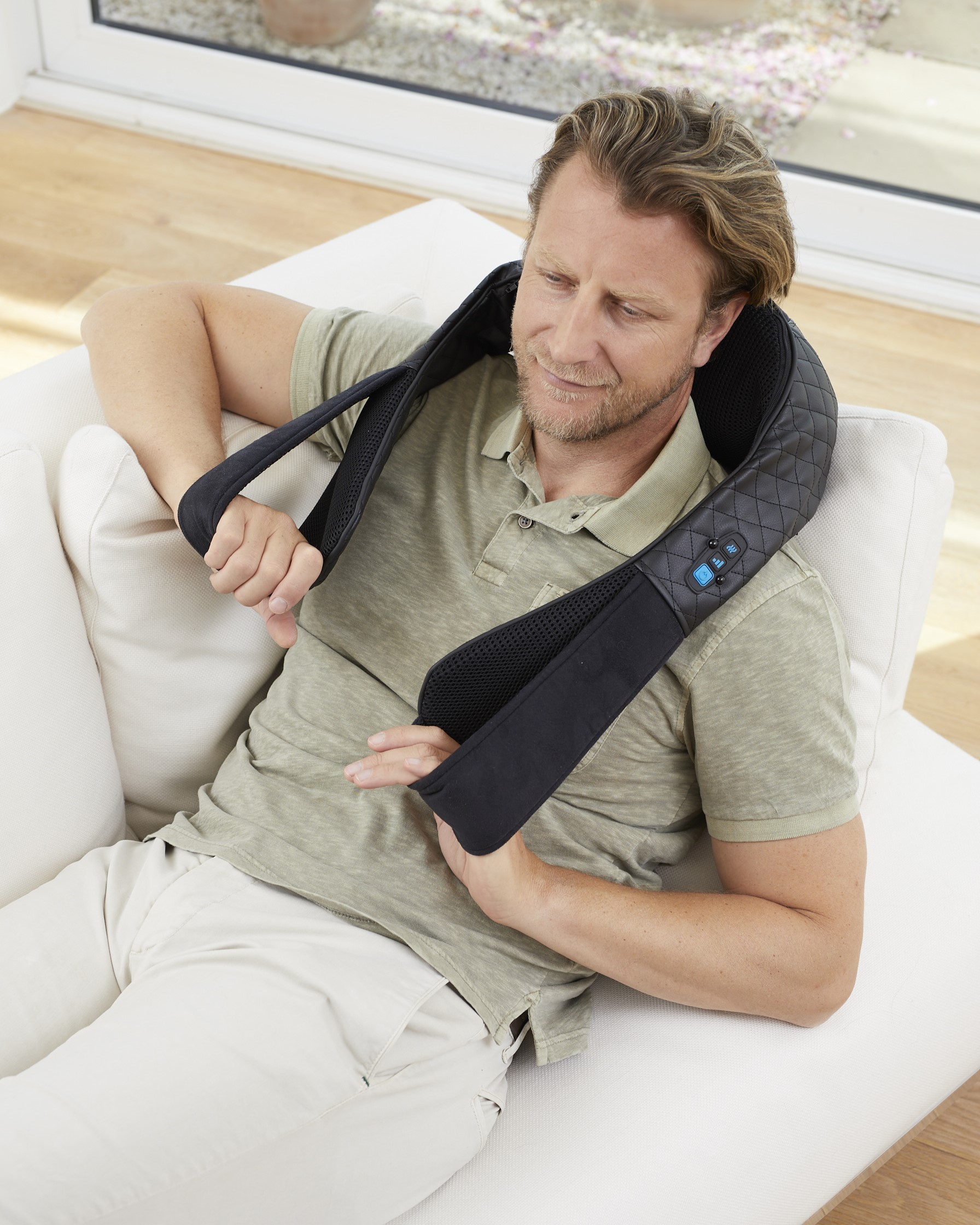 Man using medisana NMG 850 neck massager while relaxing on the couch – deep Shiatsu massage with heat function
